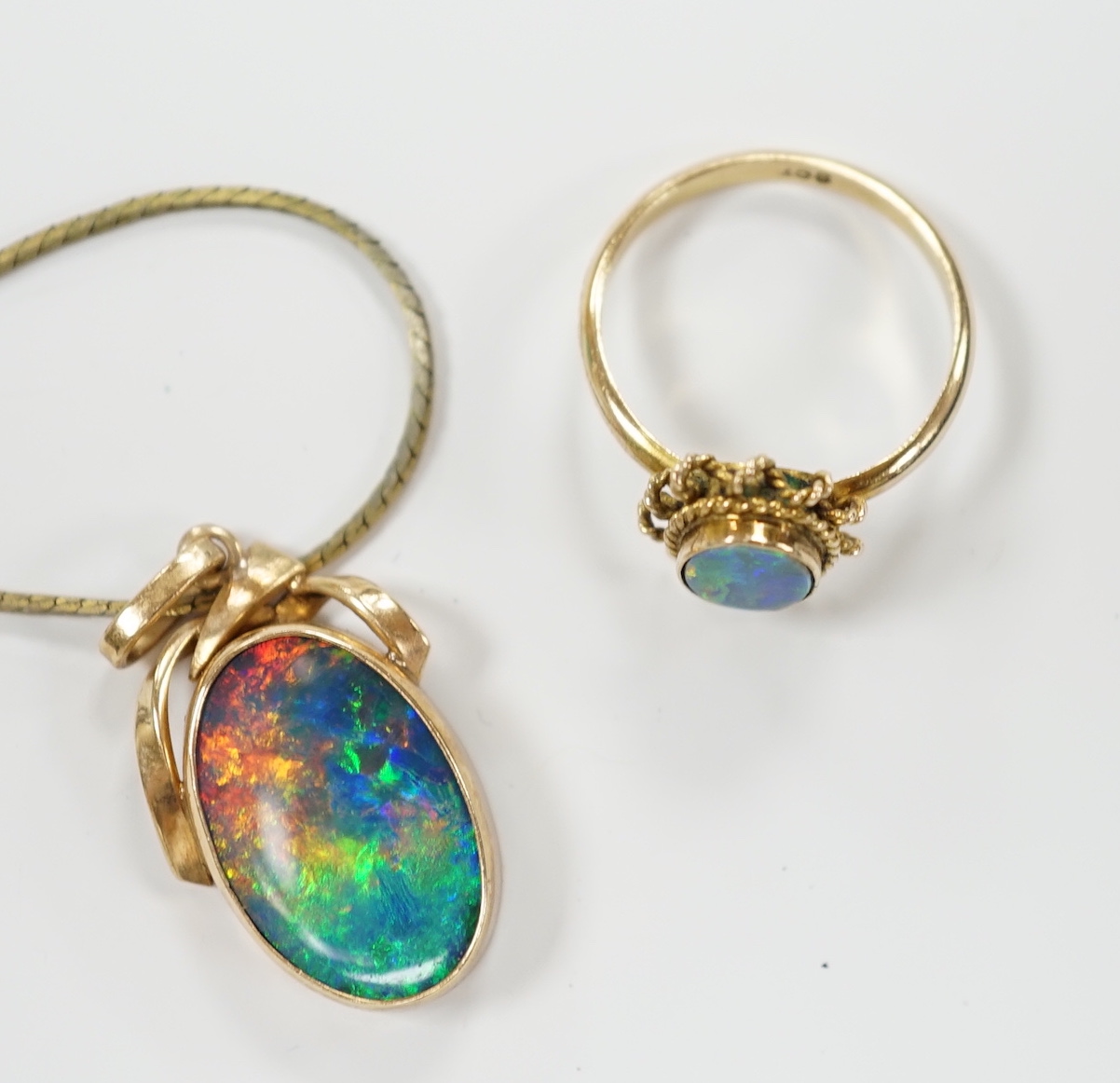 A 9ct and black opal doublet set oval ring, size L and a yellow metal and black opal doublet set pendant, on a gilt metal chain.
